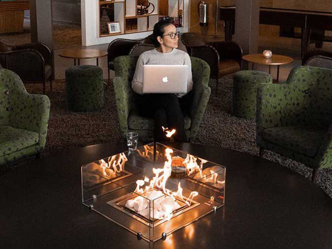 Femme assise devant la cheminée avec son ordinateur Macbook